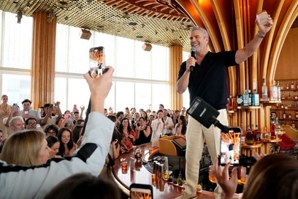 Andy Cohen stands at a bar while guests record him during the WWHL 15th Anniversay Party