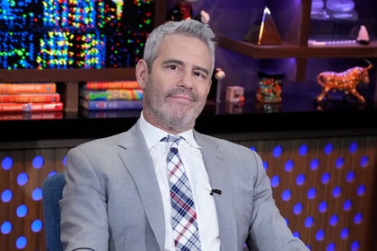 Andy Cohen sitting at the WWHL set wearing a grey suit