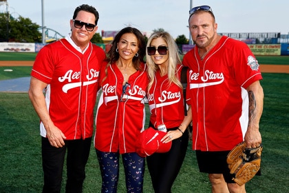 Dolores Catania, Paulie Connell, Frank Catania, and Brittany Mattessich smiling together on a softball field.