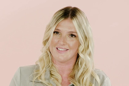 Carrie O'Niell smiling in front of a pastel pink backdrop.