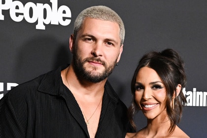 Scheana Shay and Brock Davies posing together in front of a step and repeat at an event.