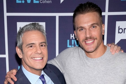 Andy Cohen and Luke Gulbranson posing together in front of a step and repeat at the Watch What Happens Live clubhouse in New York City.