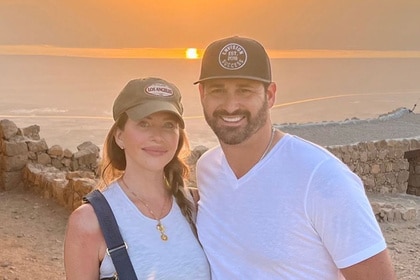 Dina Manzo and Dave Cantin smiling and posing together in front of a sunset.