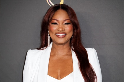 Garcelle Beauvais smiling in front of a step and repeat.