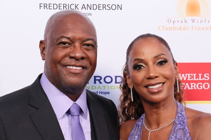 Holly Robinson Peete and Rodney Peete posing together on a step and repeat.