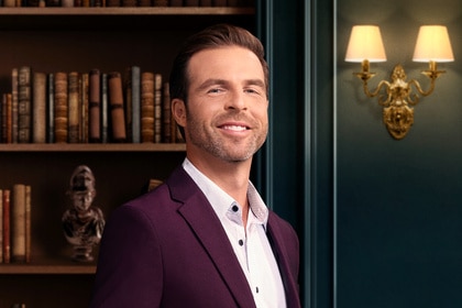 Jarrett Thomas wearing a maroon blazer in front of a book shelf