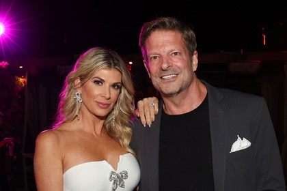 Alexis Bellino wearing a white strapless dress with a hand on John Janssen's shoulder