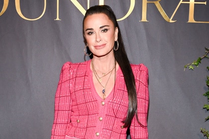 Kyle Richards wearing a bink plaid button up cardigan and a high ponytail