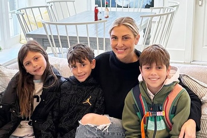 Gina Kirschenheiter, Nicholas Kirschenheiter, Sienna Kirschenheiter, and Luca Kirschenheiter smiling together on a couch.