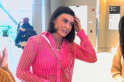 Bronwyn Newport wearing a hot pink bra and netted button up top at the airport