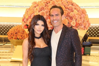 Teresa Giudice and Louie Ruelas wearing black in front of a big bouquet of flowers