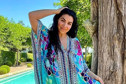 Asa Soltan wearing a blue print kaftan in front of a pool