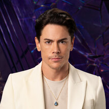 Tom Sandoval wearing a white suit while in a purple room overlooking LA.