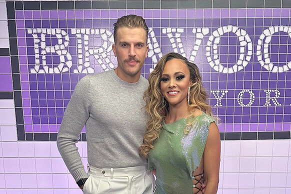 Luke Gulbranson and Ashley Darby pose together in front of a subway mosaic style Bravocon sign in New York City.