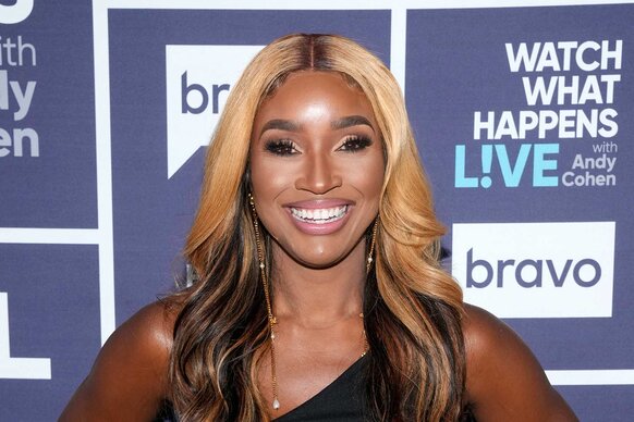 Contessa smiling in a black dress in front of the WWHL step and repeat.