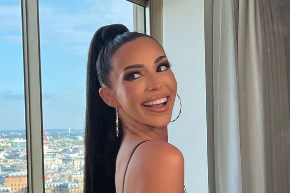 Scheana Shay smiling and posing in front of a window.