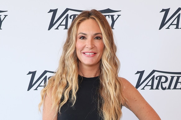 Kate Chastain wearing a black tank top in front of a Variety step and repeat