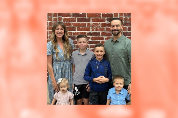 Briana Culberson posing with her family in front of a brick wall.