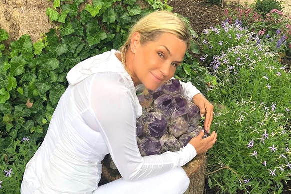 Yolanda Hadid in her yard hugging purple crystals