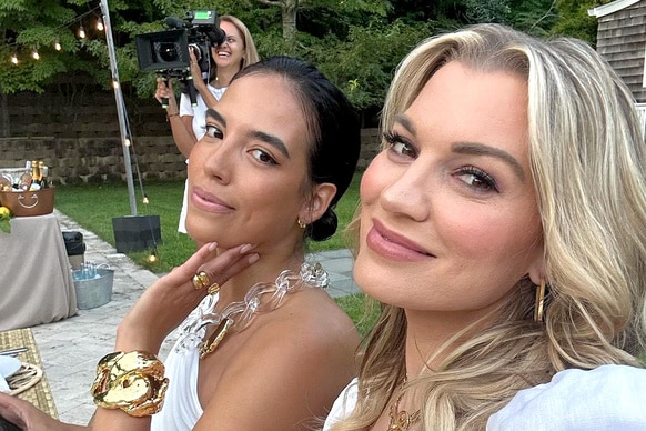 Danielle Olivera sitting at a table with Lindsay Hubbard where both are smiling and wearing white