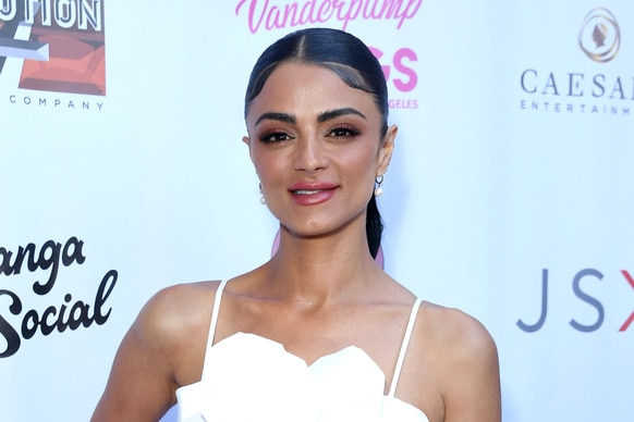 Golnesa Gharachedaghi on a red carpet wearing a white flower top