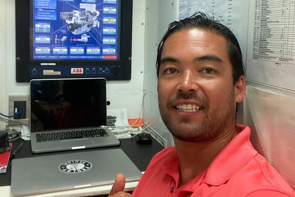 Colin Macrae in front of a computer while sailing on a yacht