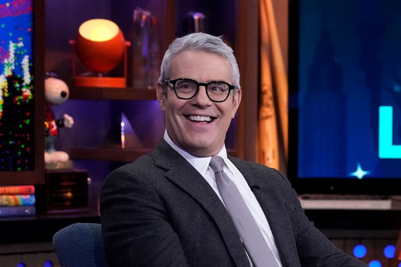 Andy Cohen smiling and wearing glasses at the Watch What Happens Live clubhouse in New York City.