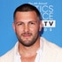 Brock Davies smiling in front of a step and repeat.