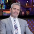 Andy Cohen sitting at the WWHL set wearing a grey suit