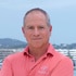 Captain Glenn Shephard posing in uniform onboard the Parsifal 3 in front of a marina.