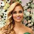 Gizelle Bryant posing in an emerald green gown in front of a backdrop of flowers.