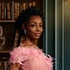 Venita Aspen wearing a pink dress standing in front of a book shelf