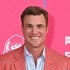 Shep Rose smiling in front of a step and repeat at Bravo Fan Fest 2024.