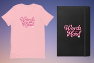 A pink tee shirt and a black journal on a fading blue to pink background that read, "Words are Hard"