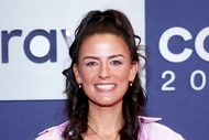 Aesha Scott smiling in front of a step and repeat at BravoCon 2023.