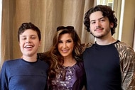 Jacqueline Laurita, with her two sons standing in front of a brown curtain.