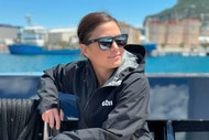 Malia White on a boat wearing a jacket and sunglesses
