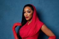 Porsha Williams wearing a red dress with a hood in front of a blue backdrop