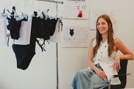 Amanda Batula sitting next to swimsuits she designed for her new swim line