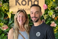 Briana Culberson and Ryan Culberson smiling together in front of a foliage wall.