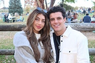 Gia Giudice and her boyfriend, Christian Carmichael sitting outside together in front of a wood log fence