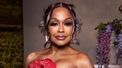 Phaedra Parks wears a beaded red and pink gown with floral embellishments in front of a vineyard-inspired set.