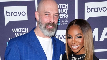 Candiace Dillard Bassett and Chris Bassett smiling in front of a step and repeat at the Watch What Happens Live clubhouse in New York City.