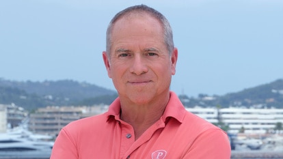 Captain Glenn Shephard posing in uniform onboard the Parsifal 3 in front of a marina.