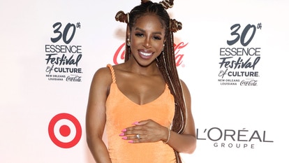 Candiace Dillard wearing an orange dress and holding her baby bump at a target event