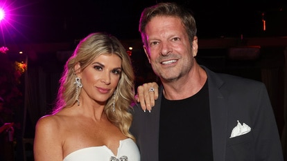 Alexis Bellino wearing a white strapless dress with a hand on John Janssen's shoulder