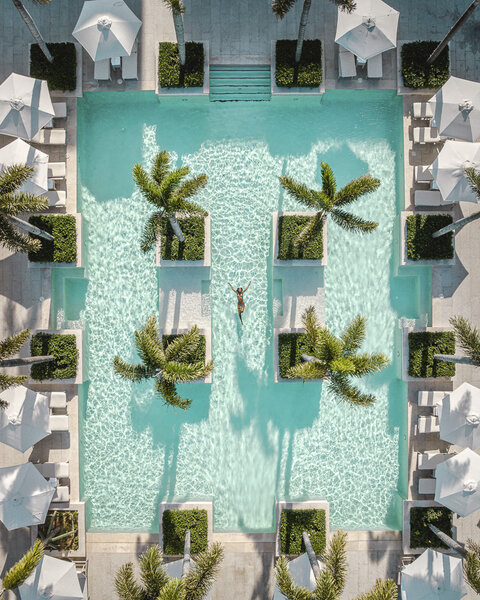 An overhead view of a pool with trees in the center and poolside with lounge chairs.