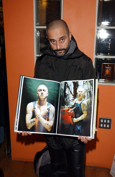 Photographer Nitin Vadukul holding up a book that shows his photography at the Proud Gallery in Camden, London.