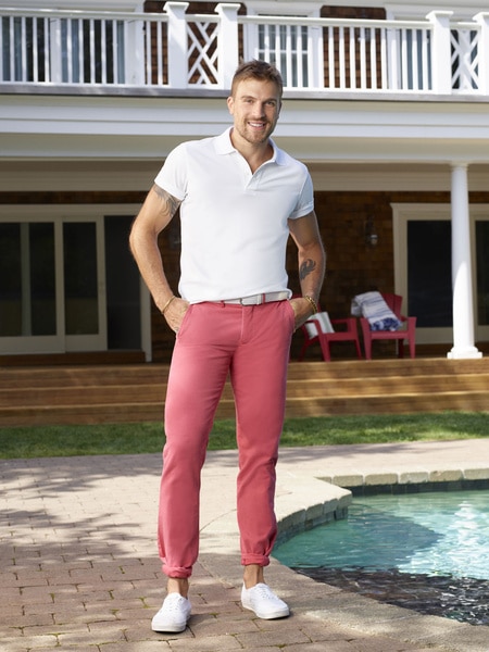 Luke Gulbranson wearing a white polo and red pants in a backyard.