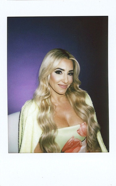 An instax of Danielle Cabral smiling and posing in front of a purple backdrop.